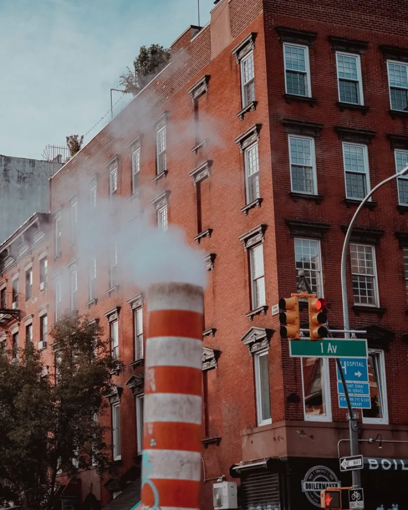 An orange and white steam stack venting on 1st Avenue