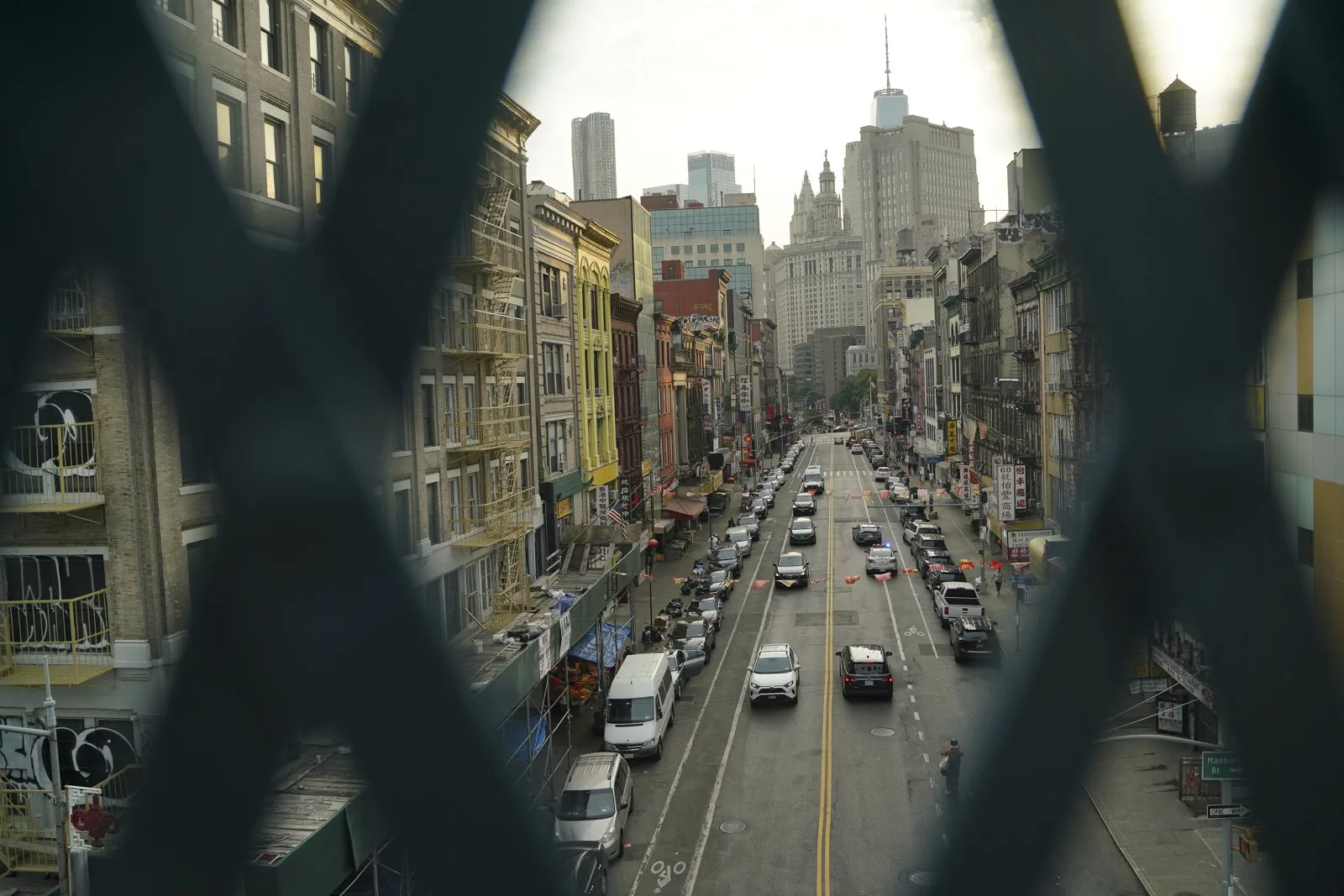 A Chinatown street seen through a fire escape lattice