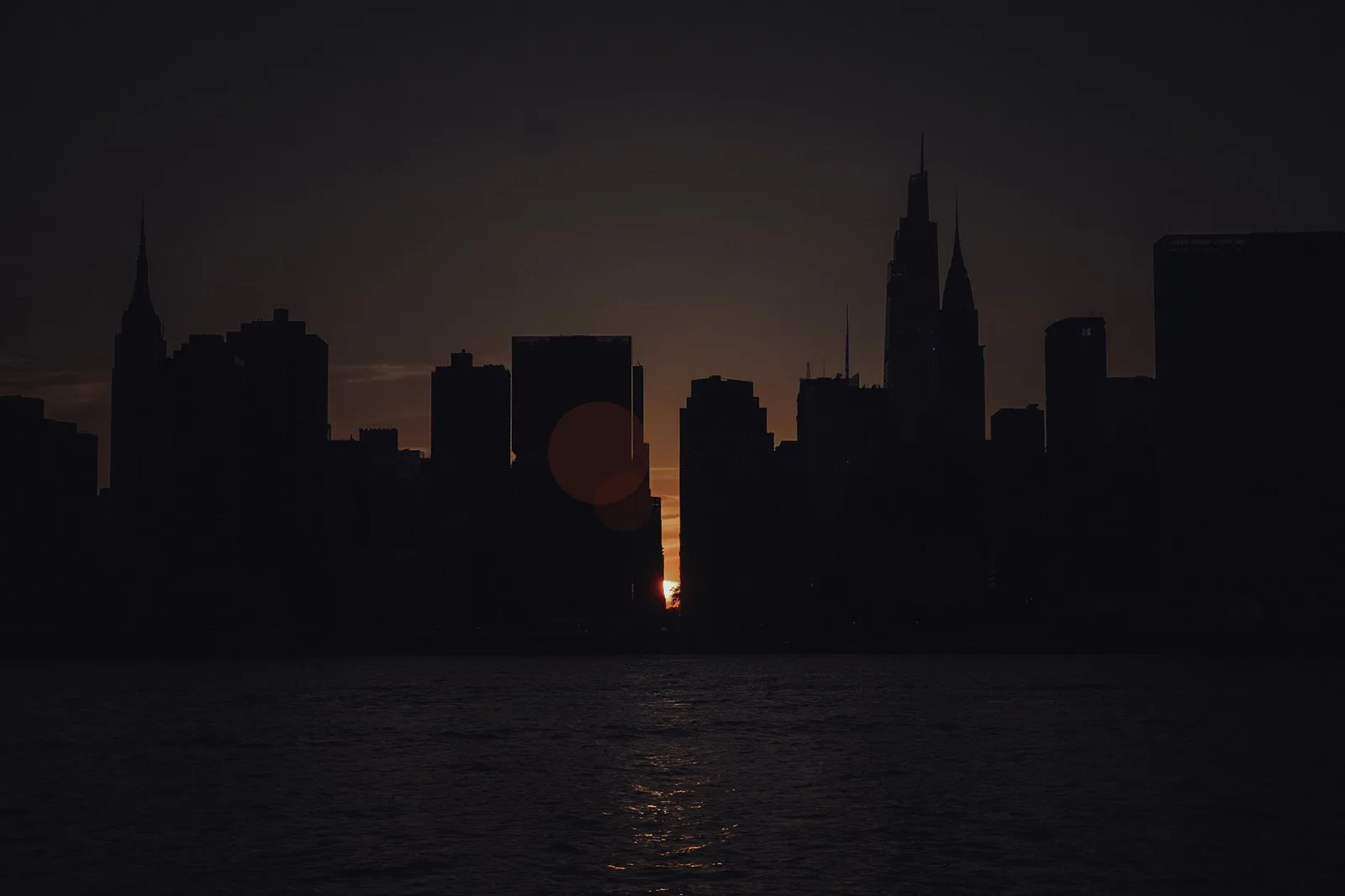 The sun setting between buildings down a Manhattan street